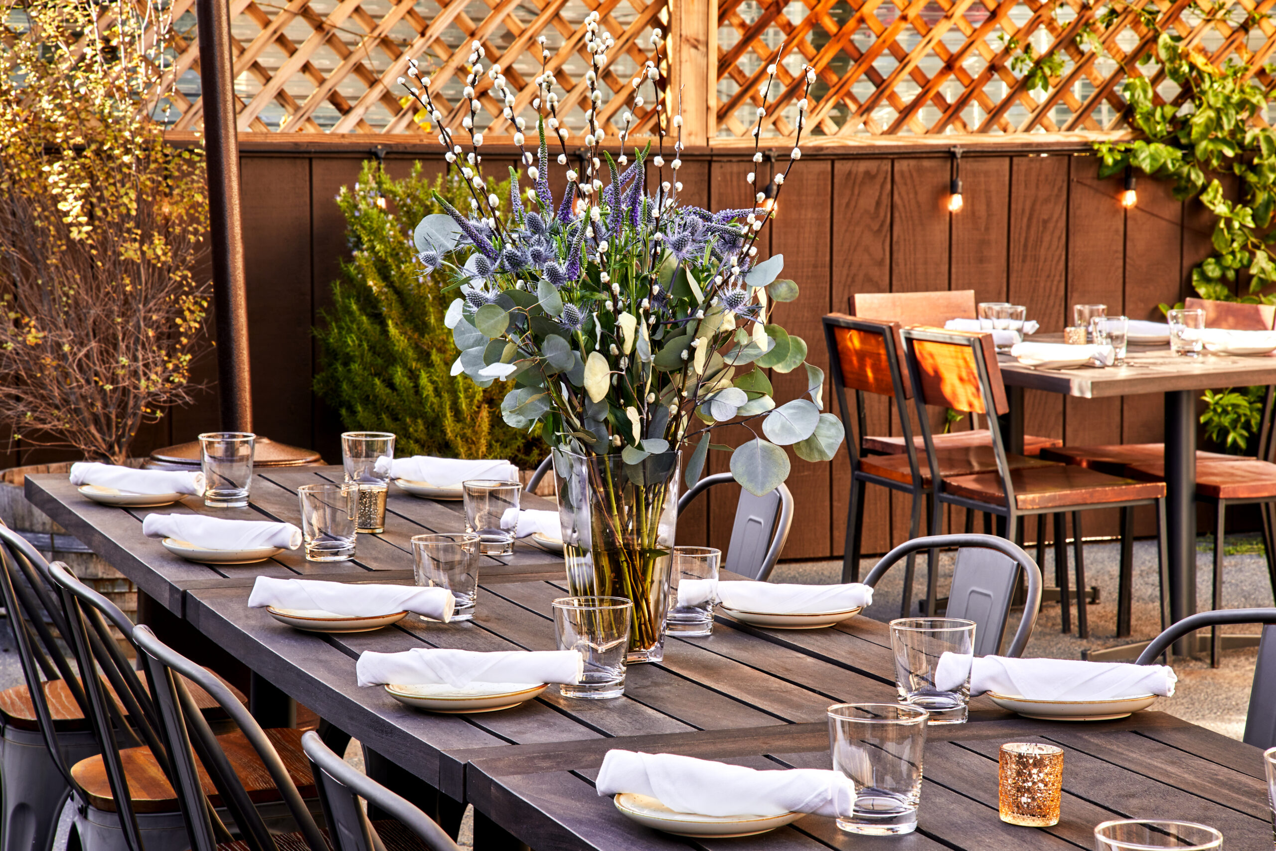 Rustic Canyon's back patio with twinkle lights, tables, chairs and a fresh eucalyptus centerpiece