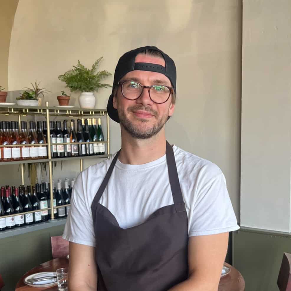 Dominic Wohlfart smiling softly in his gray apron